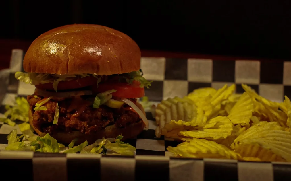 Crispy fried chicken sandwich and crinkle-cut chips on checkered paper.