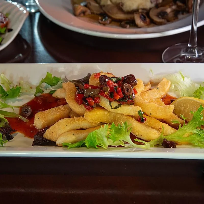 Fried calamari on greens with colorful relish, red sauce, and lemon.