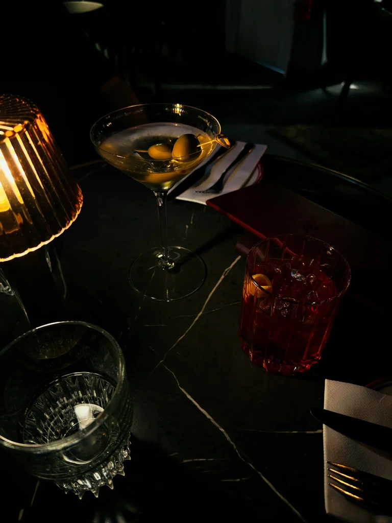 Warmly lit martini and cocktails on a dark marble table.