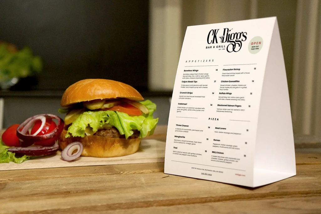 Hamburger on wooden board next to 'CK Diggs' menu.