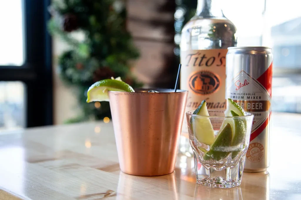 Close-up: copper mug cocktail, Tito's vodka, Stoli mixer, festive setting.