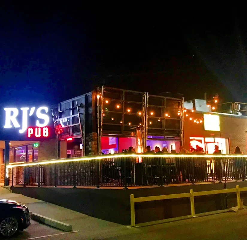 RJ's PUB exterior at night, illuminated by neon and string lights.