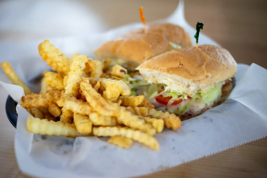 Close-up of crinkle-cut fries and a sub sandwich in a basket.