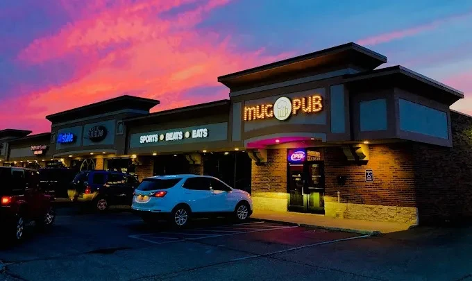 Vibrant pink and orange sunset dominates a strip mall with mug PUB.