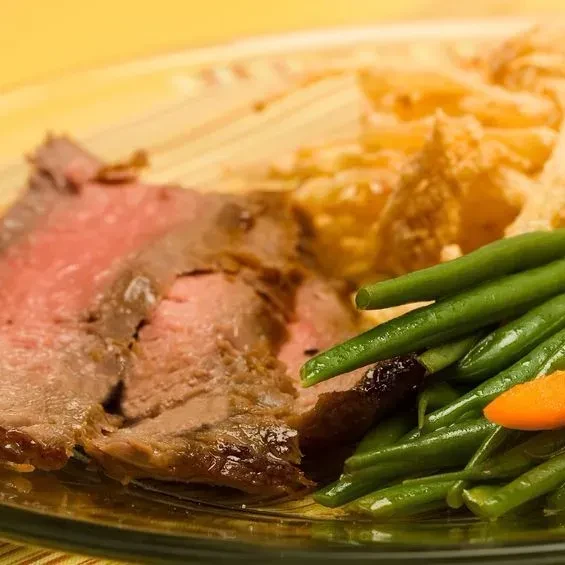 A plate of sliced roast beef, green beans, and fried potatoes.