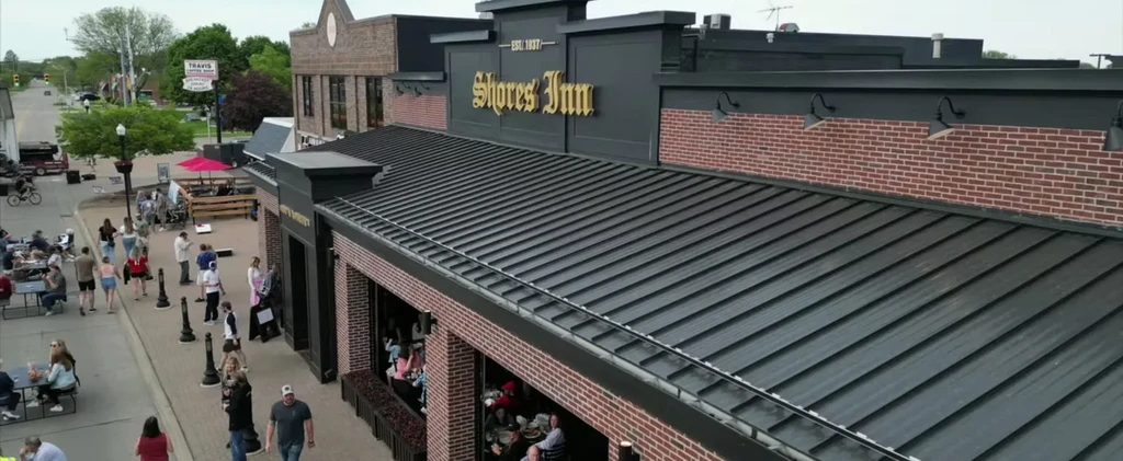 Aerial view: Shores Inn restaurant with busy outdoor dining and street.