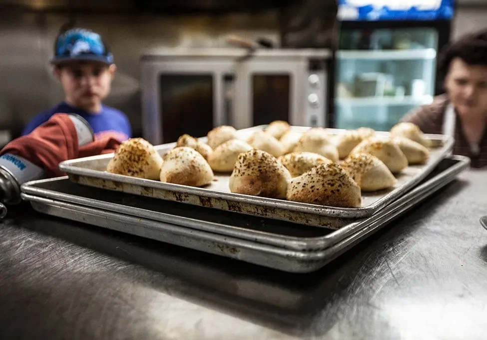 Golden-brown, seasoned baked goods on stacked trays in a professional kitchen.