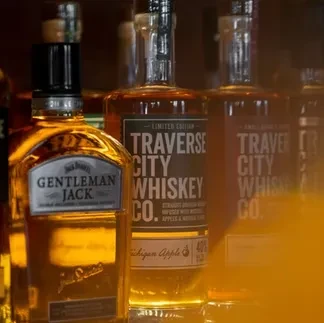 Gentleman Jack and Traverse City bourbon whiskey bottles in a dim bar.