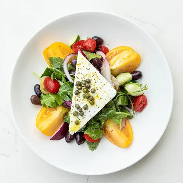 Salad with feta cheese and capers, tomatoes, olives, and greens.