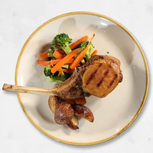 Large bone-in chop, grilled fruit, potatoes, and vegetables on a plate.