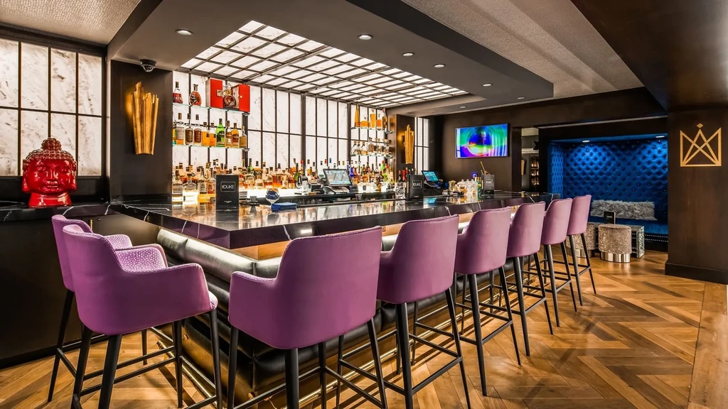 Dark marble bar, purple stools, liquor bottles, red Buddha head.