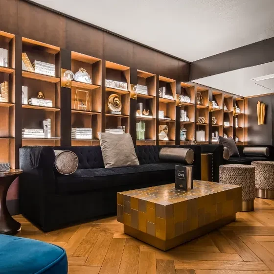 Sophisticated lounge with velvet sofa, leopard ottomans, and lit display shelves.