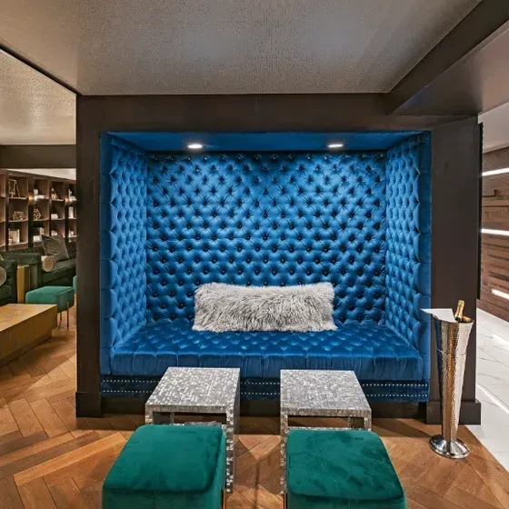 Blue velvet booth with green ottomans and mosaic tables.
