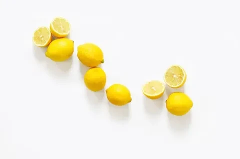 Nine bright yellow lemons, six whole and three halved, on white.