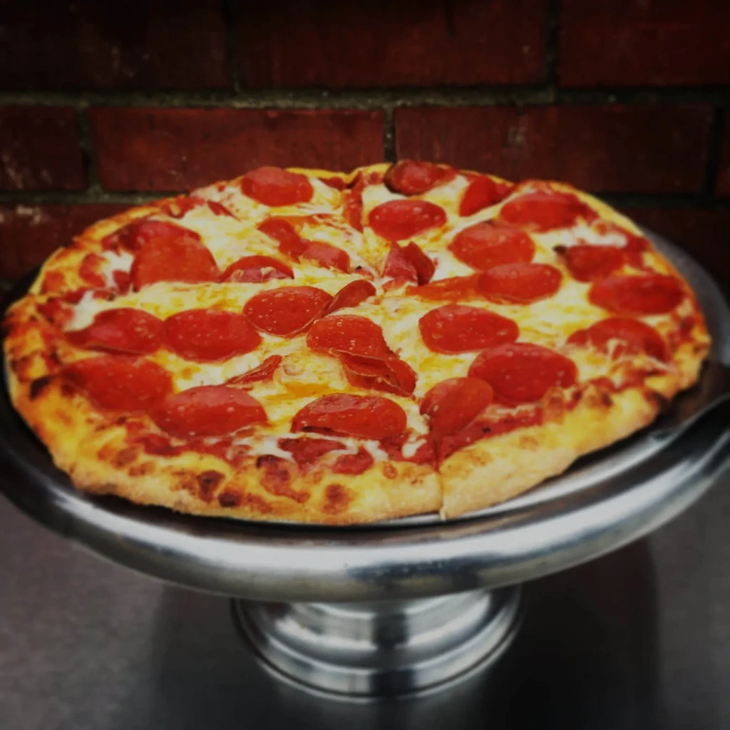 Sliced pepperoni pizza with melted cheese on a silver stand.