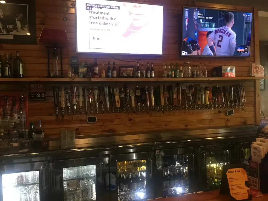 Bar with numerous beer taps, liquor bottles, and two TVs.