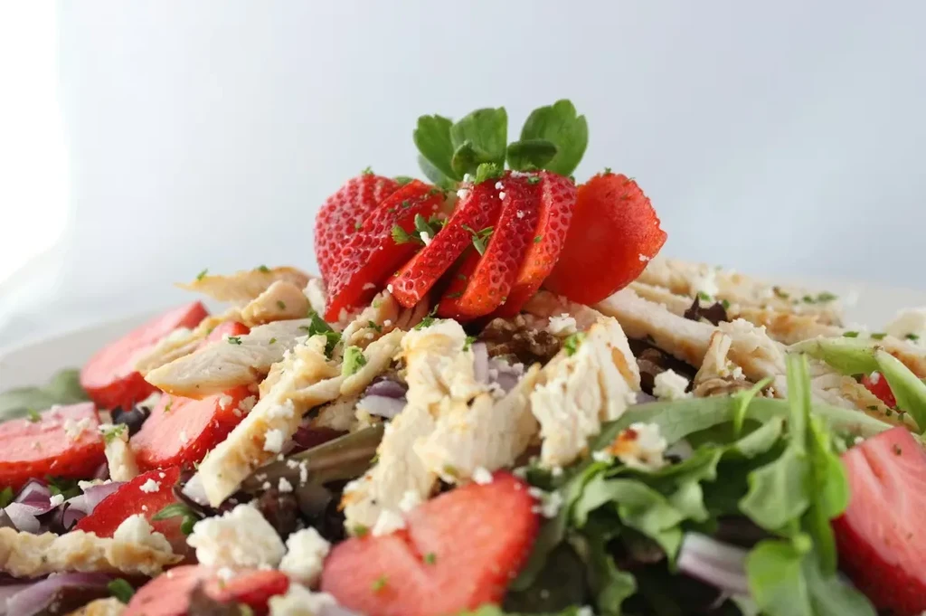 Salad with chicken, strawberries, feta, red onion, and mixed greens.