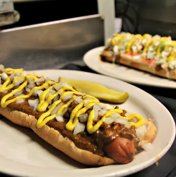 Chili dog with chunky chili, mustard, diced onions, and pickle.
