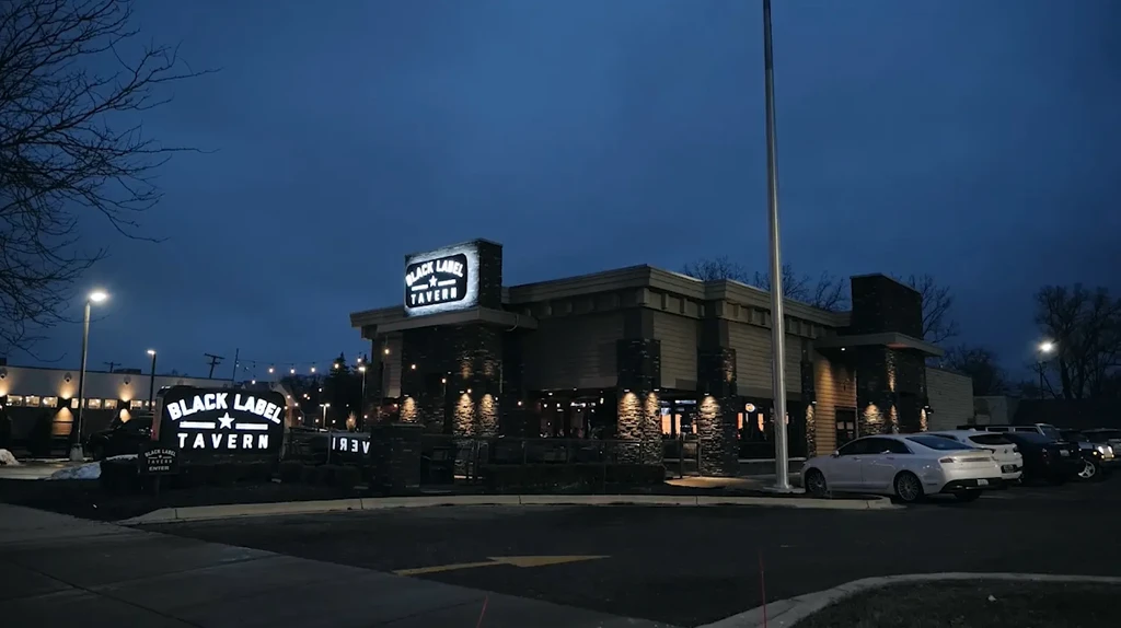 Modern Black Label Tavern building brightly lit at night with cars.