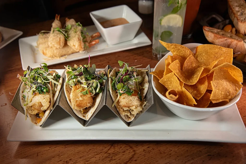 Three crispy tacos with slaw, tortilla chips, and fried shrimp.