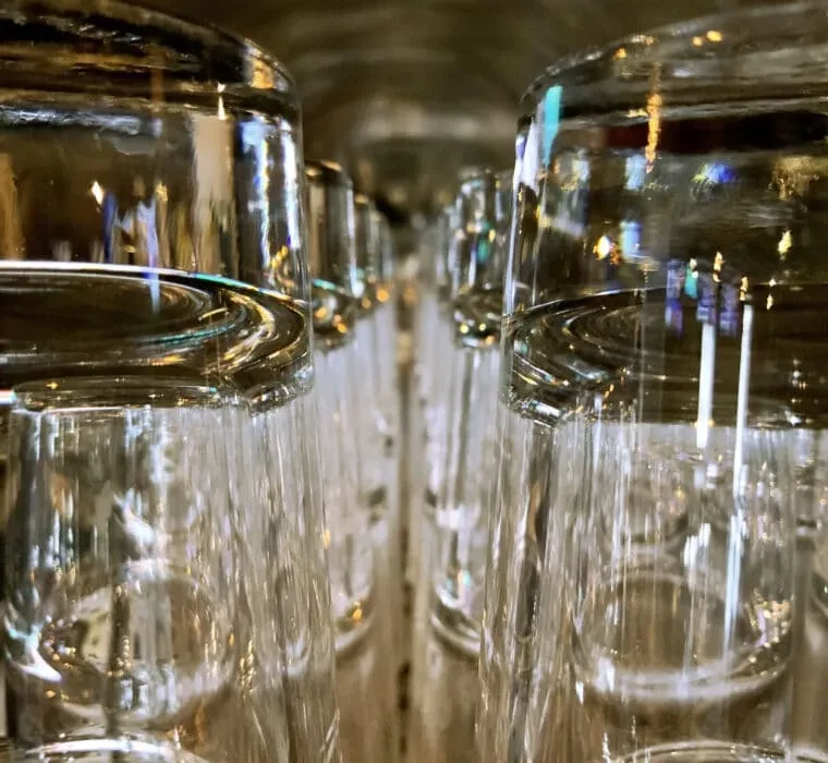 Close-up of a long line of clear drinking glasses reflecting light.