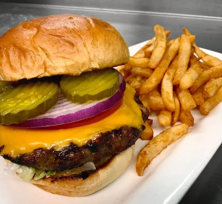 Cheeseburger with melted cheese, pickles, red onion, and crispy fries.