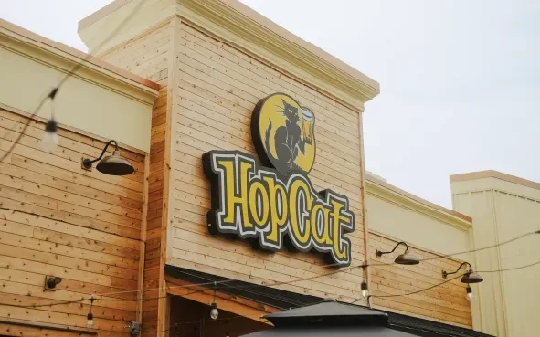 HopCat building exterior: light wood, yellow sign, cat logo, string lights.