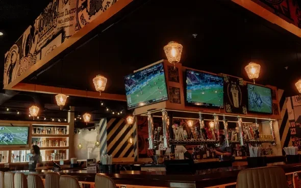 Dark-wood bar with beer taps, sports TVs, and warm lighting.