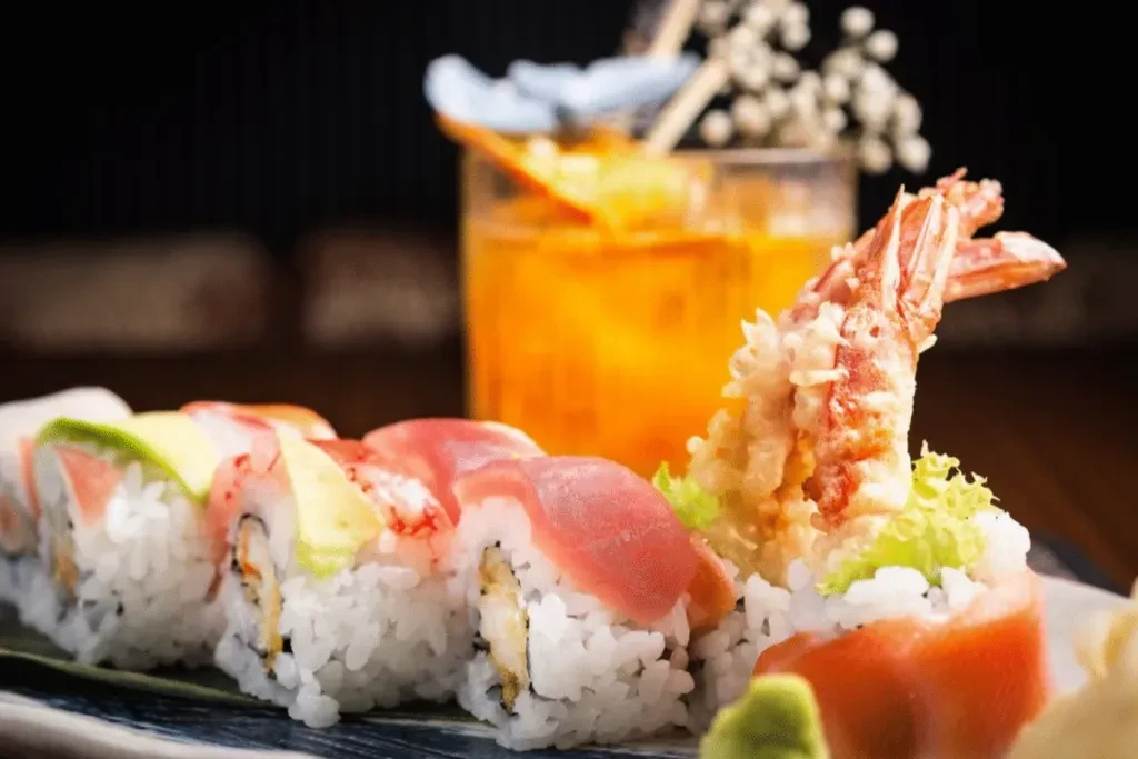 Fresh sushi rolls with avocado, tuna, shrimp, and an amber cocktail.