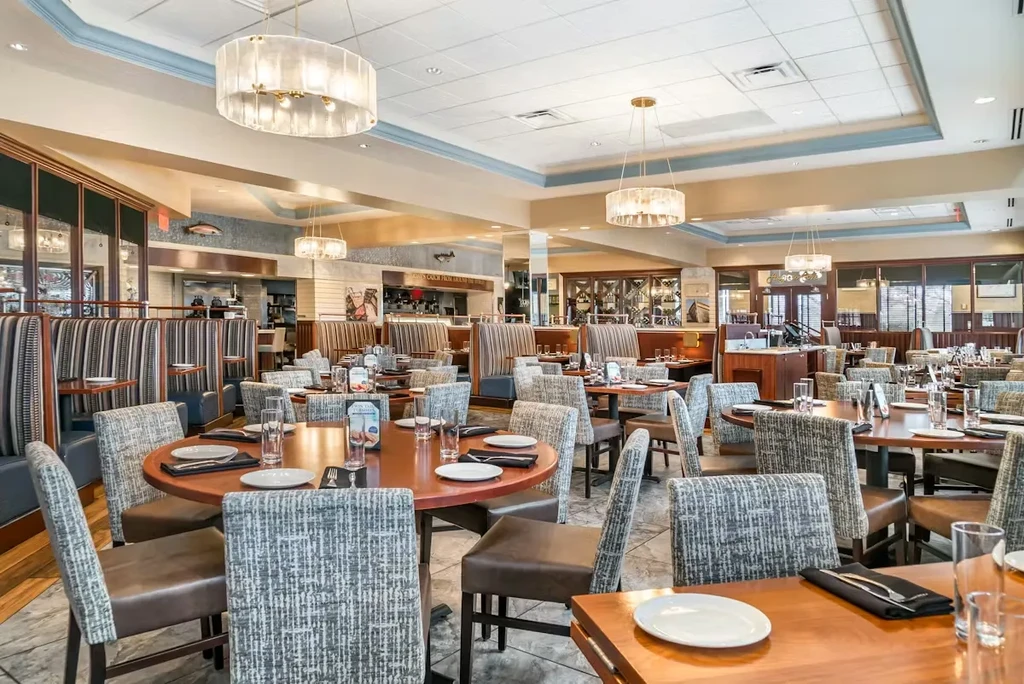 Spacious, well-lit restaurant dining room with set tables and nautical decor.