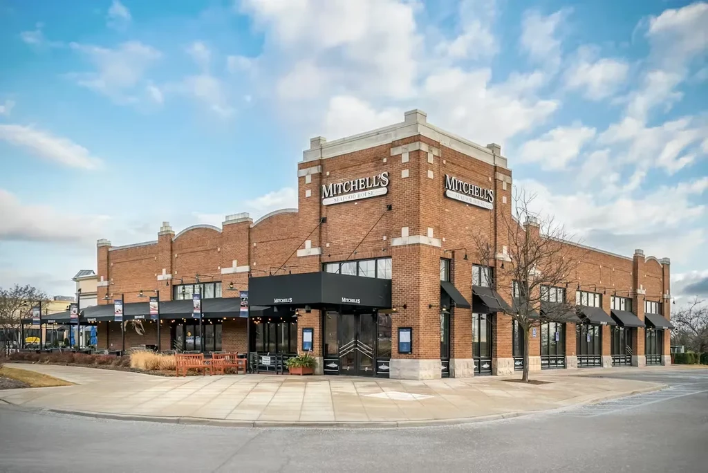 Modern brick Mitchell's Seafood House with black awnings and outdoor seating.