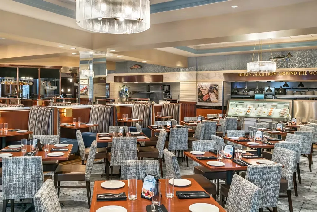 Modern restaurant interior with set tables, bar, and seafood display case.