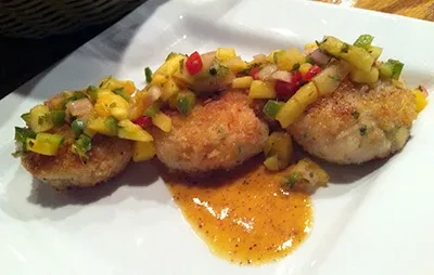 Three golden cakes with colorful salsa and sauce on a plate.