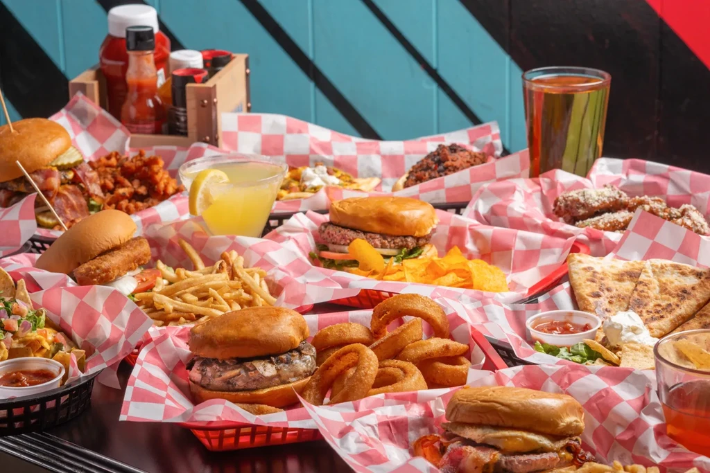 A table full of casual comfort food: burgers, fries, nachos, wings.