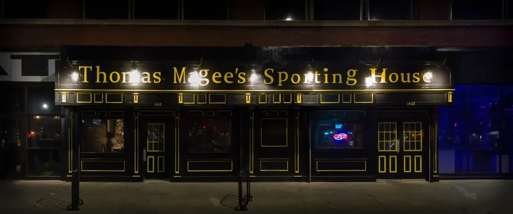 Exterior of Thomas Magee's Sporting House at night, dark with yellow trim.