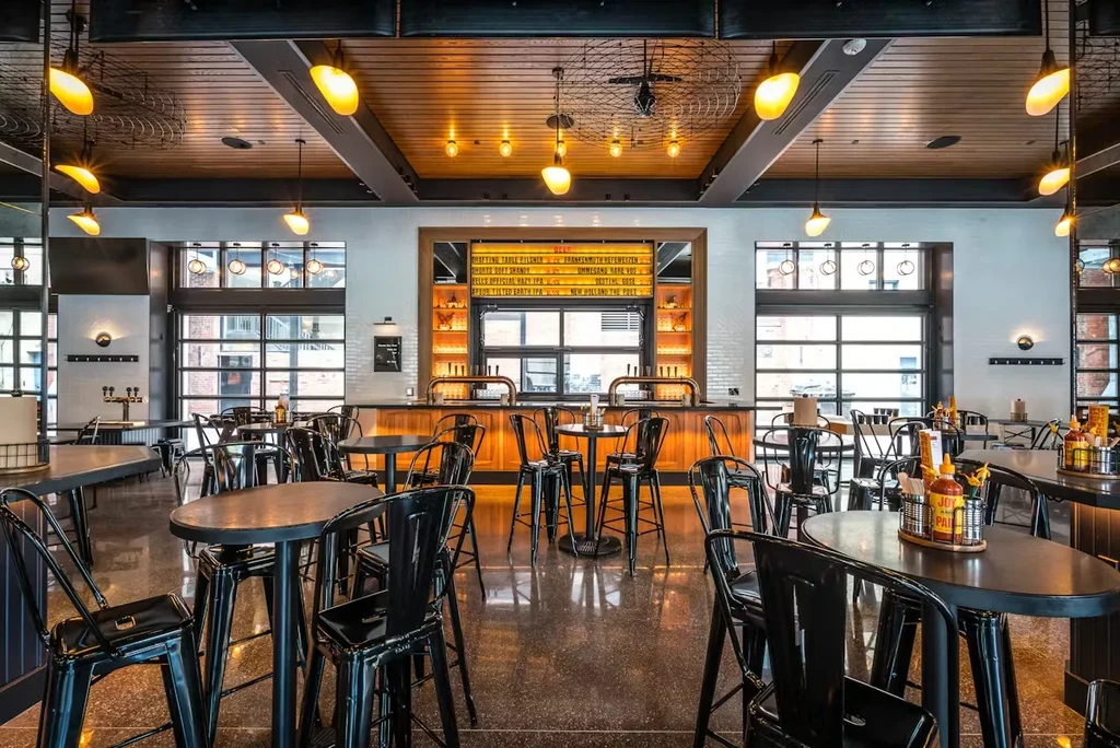 Empty modern industrial restaurant interior with bar, tables, and unique lights.