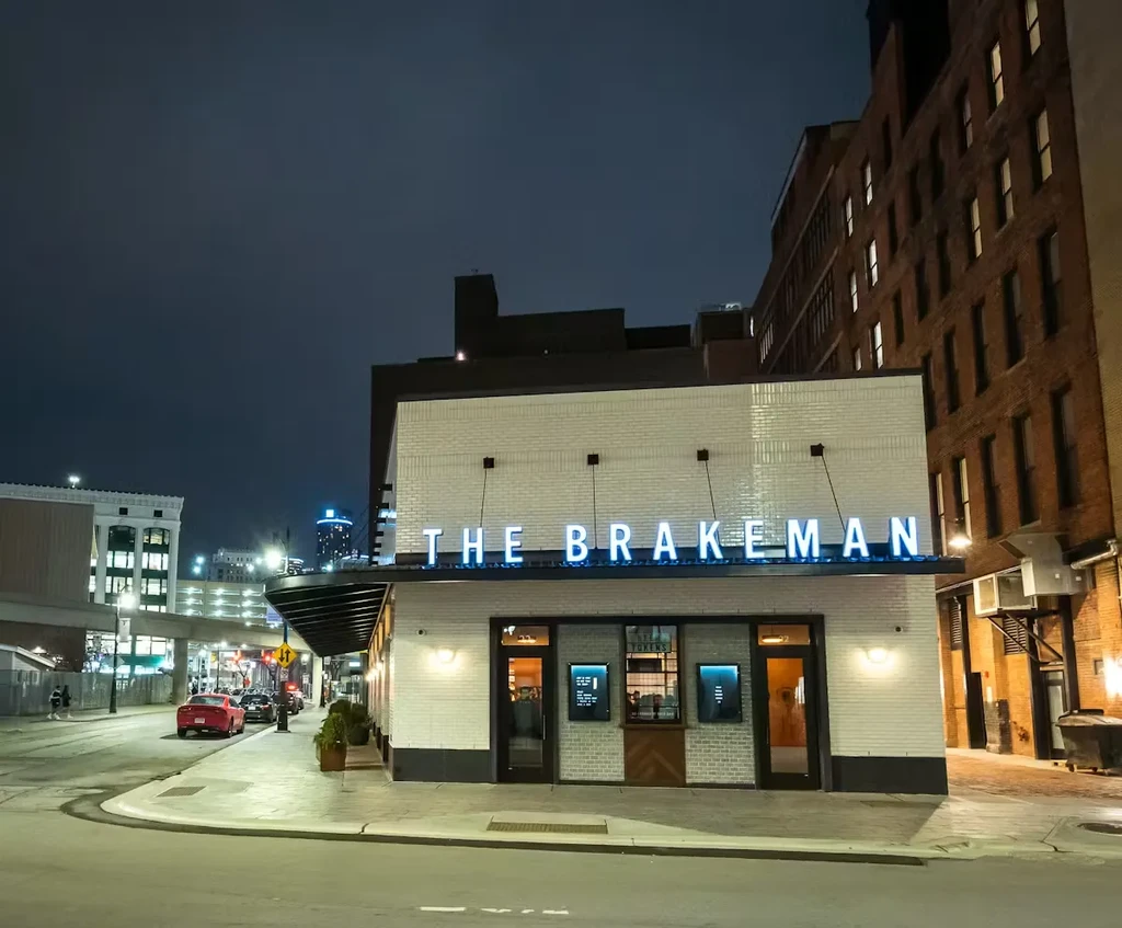 Modern 'THE BRAKEMAN' with blue neon sign in an urban night scene.