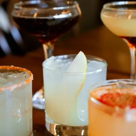 Close-up of four diverse cocktails in glasses on a table.