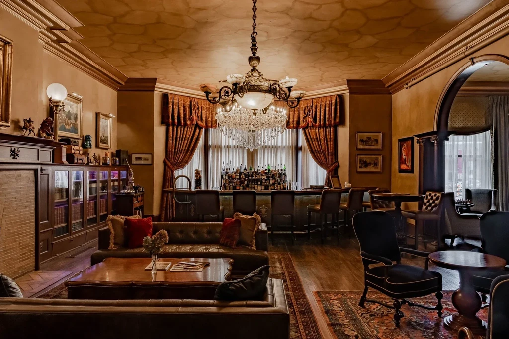Luxurious bar lounge with crystal chandelier, stocked bar, and plush seating.