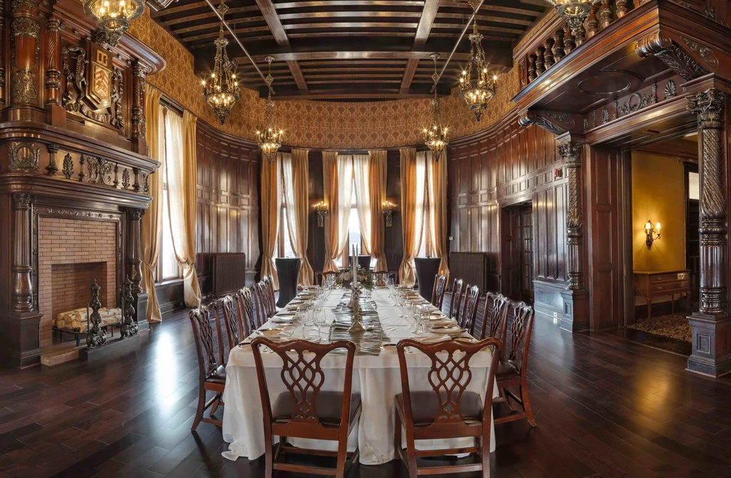 Formal dining room with set table, wood paneling, fireplace, chandeliers.