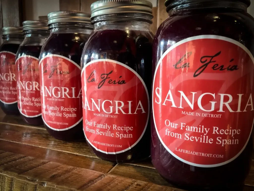 Five varying sizes of La Feria sangria jars on wood.
