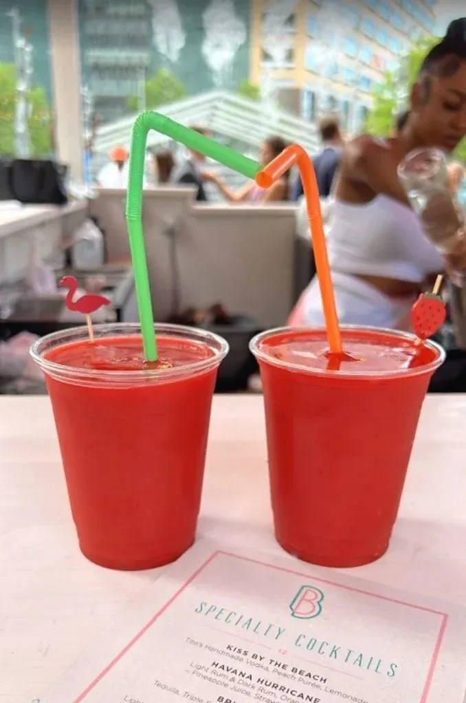 Two red Specialty Cocktails with flamingo and strawberry stirrers.