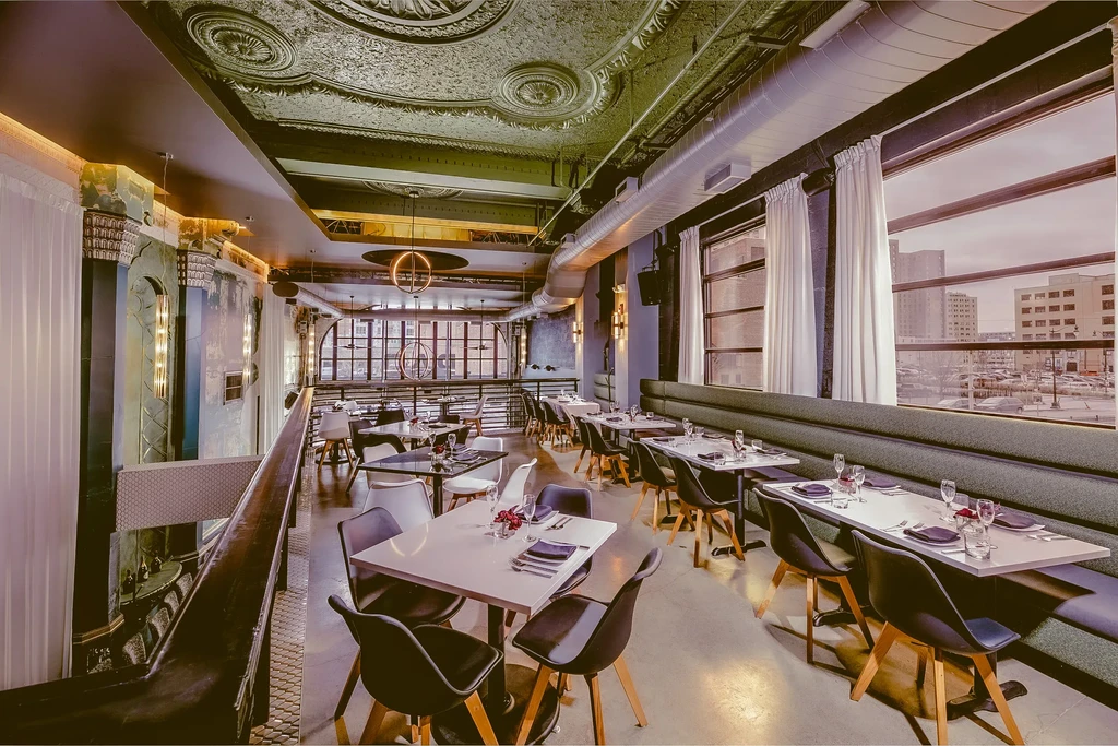 Empty, multi-level restaurant interior blending industrial and ornate design.