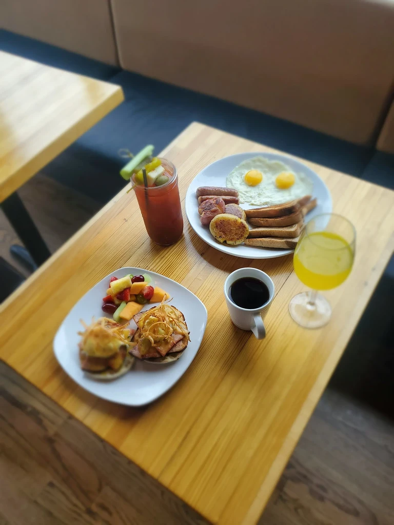 Two plates of eggs and fruit brunch on a restaurant table.