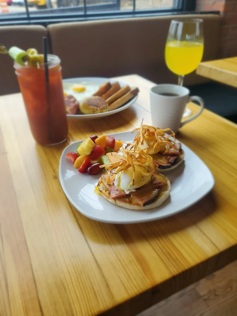 Restaurant table with Eggs Benedict, traditional breakfast, coffee, and Bloody Mary.
