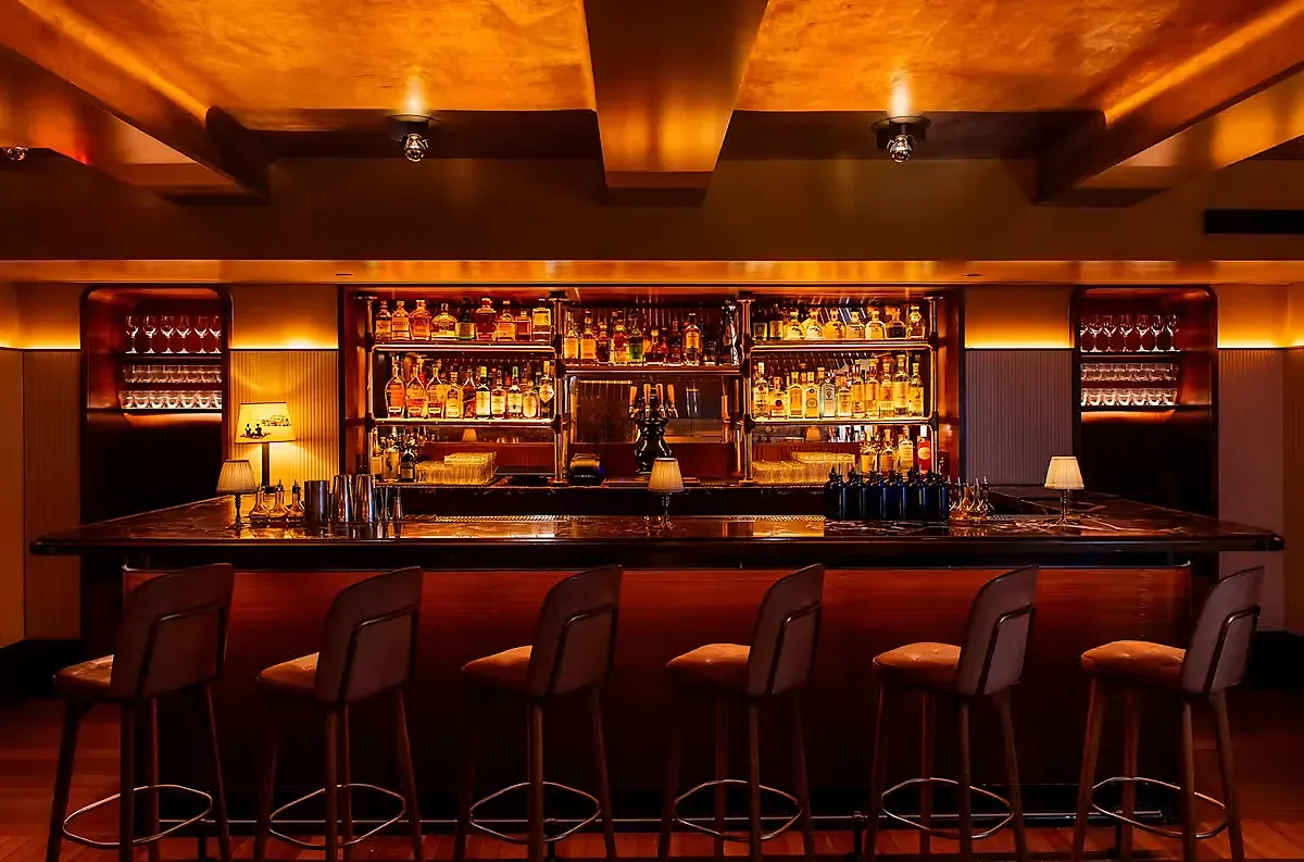 Central bar with six stools and illuminated bottle display behind