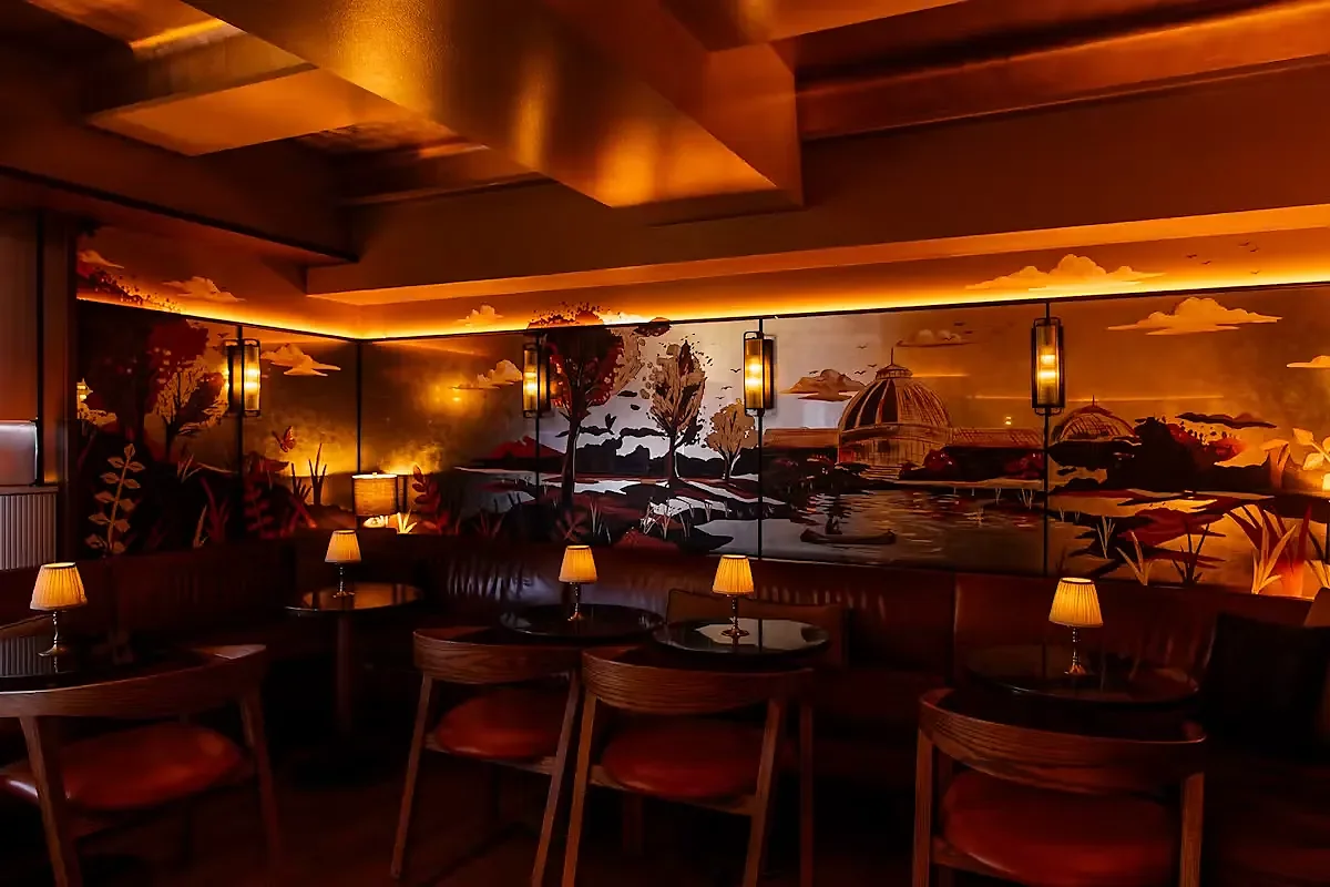 Lounge banquette seating with painted landscape mural and table lamps