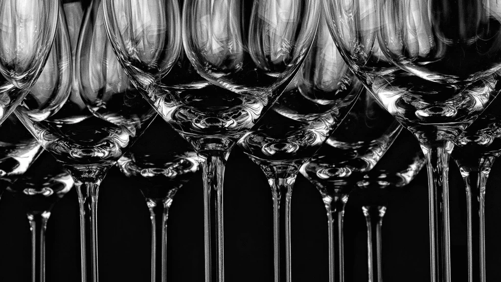 High-contrast, black and white photo of symmetrical wine glasses, from below.