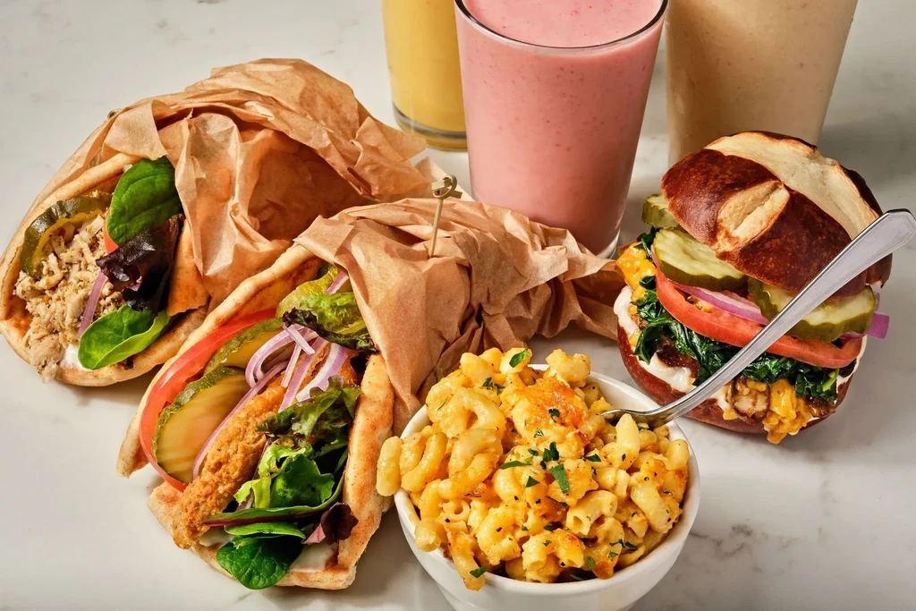 Vibrant spread of macaroni, wraps, a burger, and colorful smoothies.
