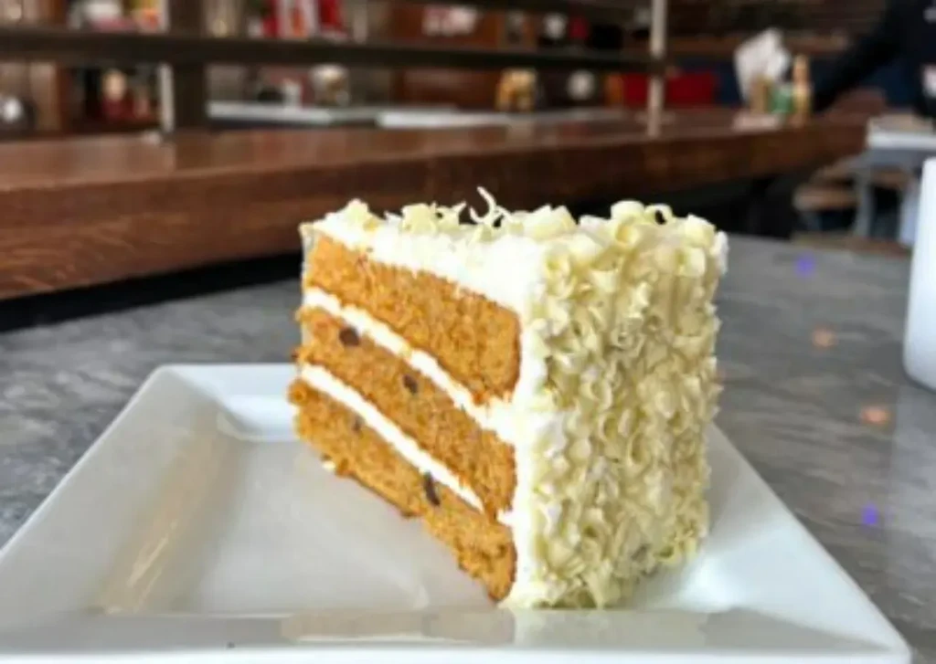 Slice of layered cake with white frosting and white chocolate curls.